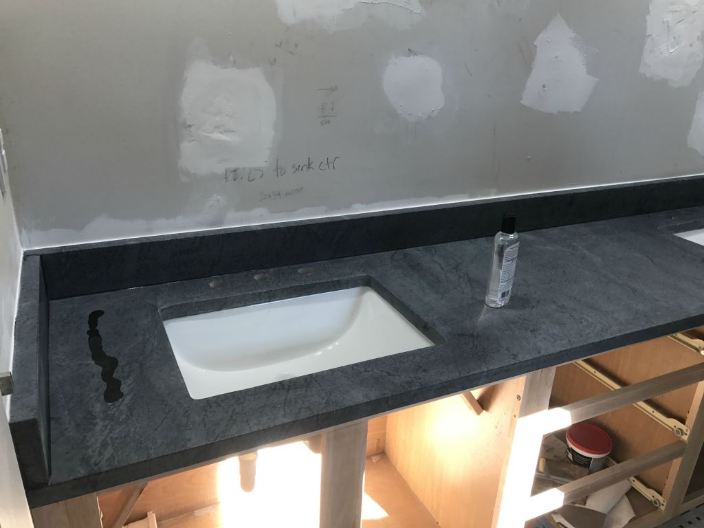 The soapstone countertop arrives (with sinks installed) and we start to oxidize it with mineral oil.  You can see the squiggle of oil on the left.